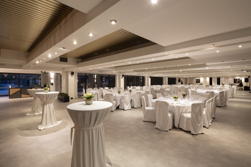 De zaal met hoge statafels en gedekte tafels, klaar voor een receptie